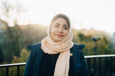 Thoughtful teenage girl wearing hijab looking away against sky