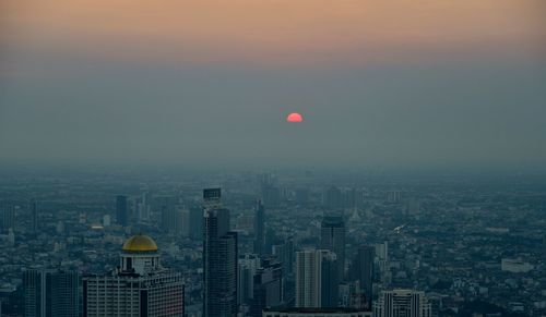 Aerial view of buildings in city at sunset