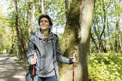 Portrait woman trekking with sticks, happy caucasian 36 yo hiking female, nordic walking with sticks