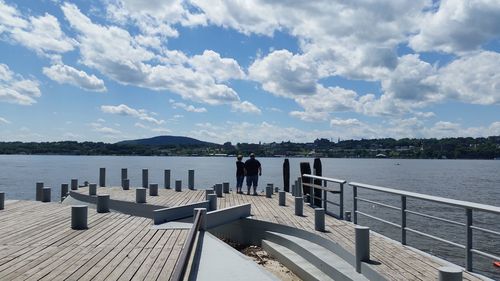 Man standing on jetty by sea against sky