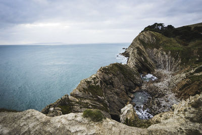 Scenic view of sea by cliff against sky