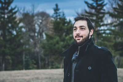 Portrait of young man standing against trees