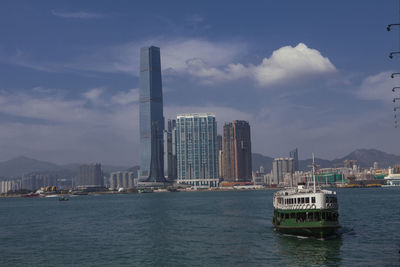 Sea by modern buildings in city against sky