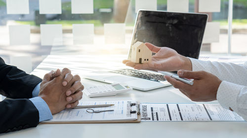 Cropped image of man holding paper on table