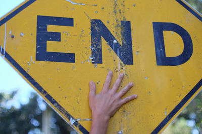 Cropped hand touching road sign