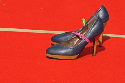 High angle view of shoes on floor against red background