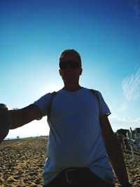 Man standing at beach against clear blue sky