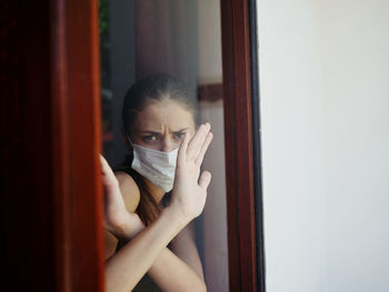 Portrait of young woman on window