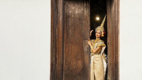 An asian woman wearing a traditional costume for ramya is hidden at the door.