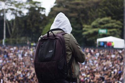 Rear view of man with backpack wearing hood in city