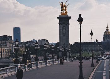 Statue in city against sky