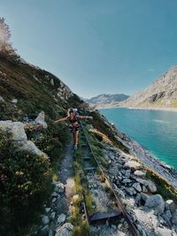 Man standing on rock by mountain against sky