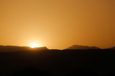 Scenic view of silhouette mountain against orange sky