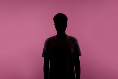 Rear view of silhouette man against pink background
