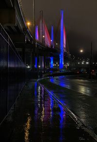 Illuminated bridge in city during rainy season at night