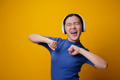 Portrait of teenage girl standing against yellow background