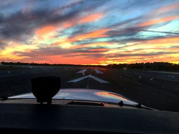 Cars on road against sky during sunset