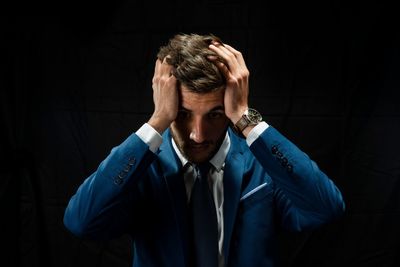 Portrait of a young man making face against black background