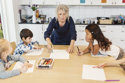 Senior female teacher with students in drawing class