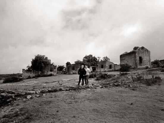 REAR VIEW OF MAN WALKING ON FIELD AGAINST CLOUDY SKY