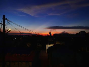 Silhouette bridge against dramatic sky during sunset