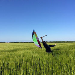 Man holding umbrella while standing amidst crops on agricultural field