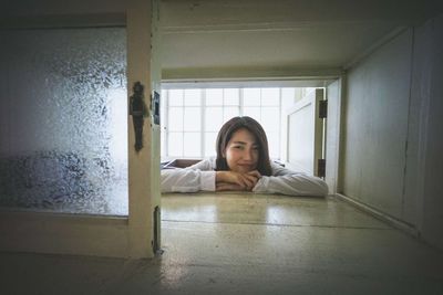 Portrait of young woman sitting on window