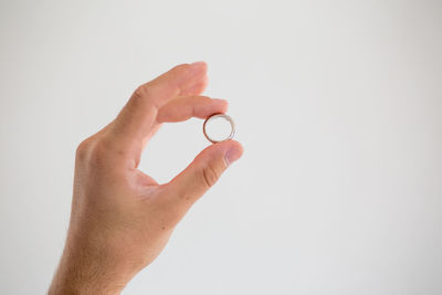 Close-up of hand holding leaf over white background