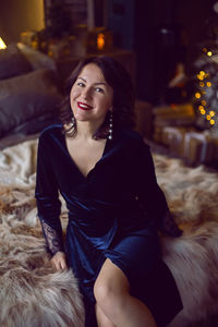 Woman in blue long dress sitting on bed at christmas