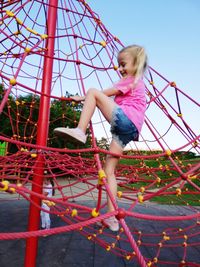 Low angle view of girl playing on playground against sky