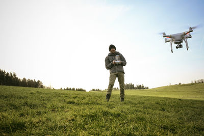 Man on a meadow flying drone while his dog watching