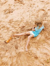 High angle view of girl playing on sand at beach