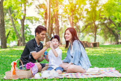 Young couple sitting on plant against trees