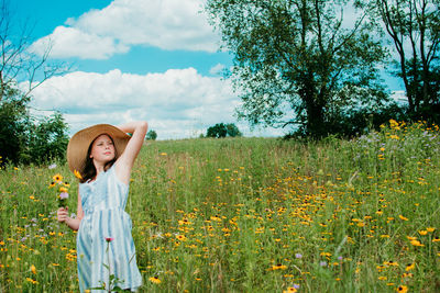 Woman standing on grassy field against yellow flowers