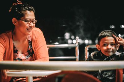 Close-up of mother and son sitting at table in restaurant during night