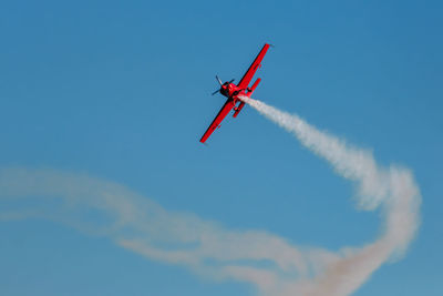 Low angle view of airplane flying against blue sky