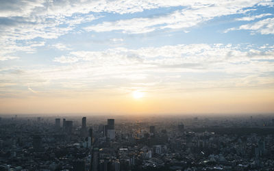 Aerial view of cityscape against cloudy sky