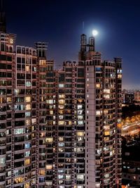 Modern buildings in city against sky at night