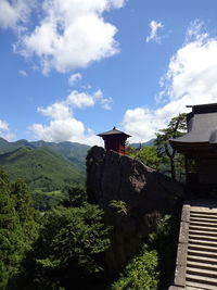 House amidst trees and buildings against sky
