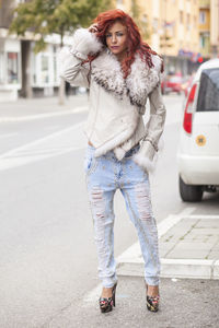Portrait of young woman in fur coat standing on city street