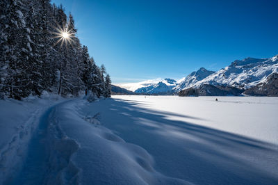 Panorama of lake sils, in engadine, switzerland, frozen and snowy, and the mountains above.