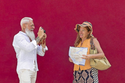 Midsection of a smiling young woman standing against red wall