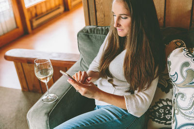 Woman using phone while sitting on sofa at home