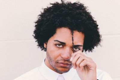 Portrait of young man with curly hair against white background