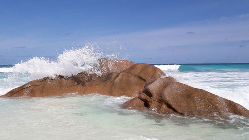 Sea waves splashing on shore against sky