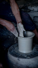 Midsection of man working on pottery wheel in workshop