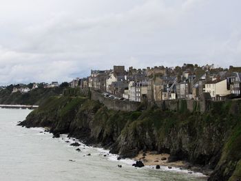 Town on cliff against cloudy sky