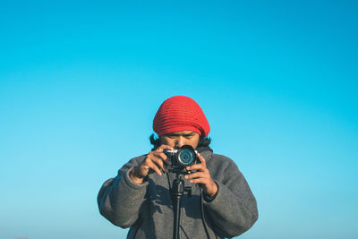Woman photographing against clear blue sky