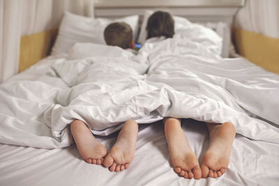 Two siblings watching video in their mobile device in the bed, gadget dependence and addiction