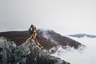 Young woman on rock against clear sky